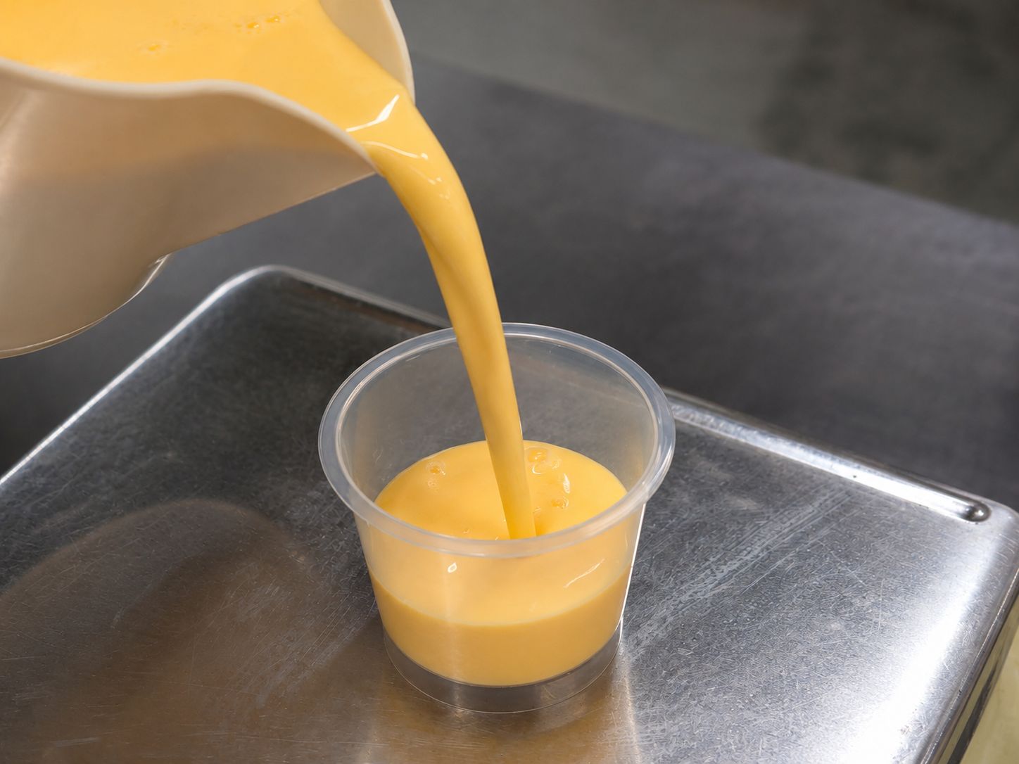 プリン液をカップに注ぎ込む様子